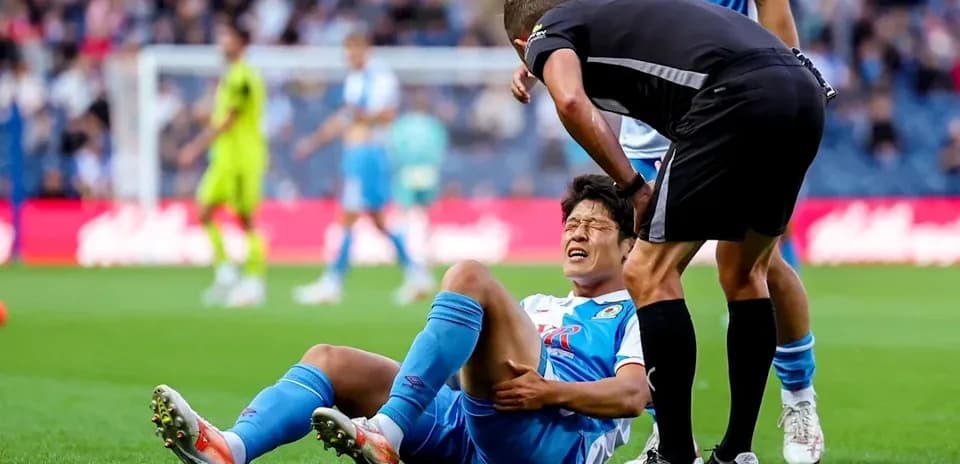 Jugador caído con dolor siendo atendido por el árbitro