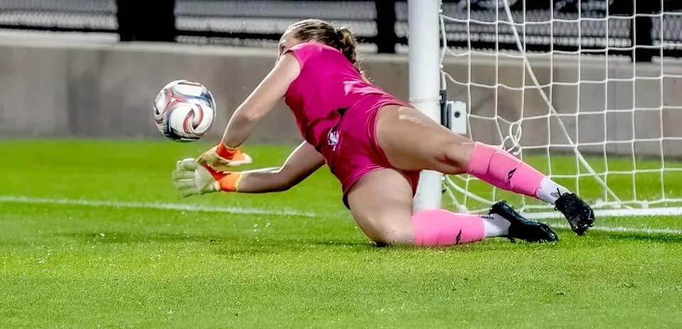 Portera tratando de detener el balón en el gol