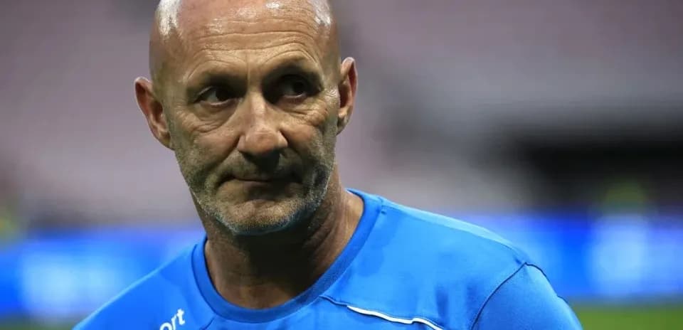 Entrenador con camiseta azul en el campo de fútbol