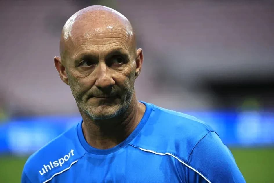 Entrenador con camiseta azul en el campo de fútbol