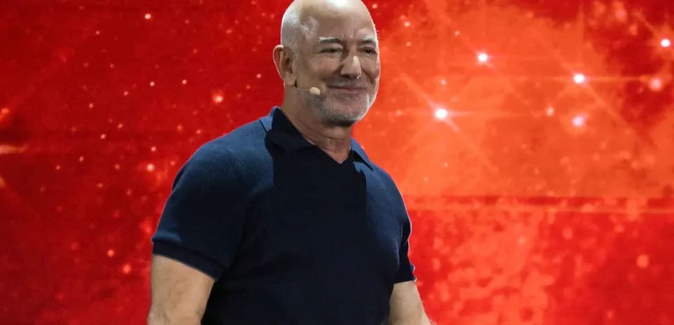 Hombre hablando en un evento con fondo rojo