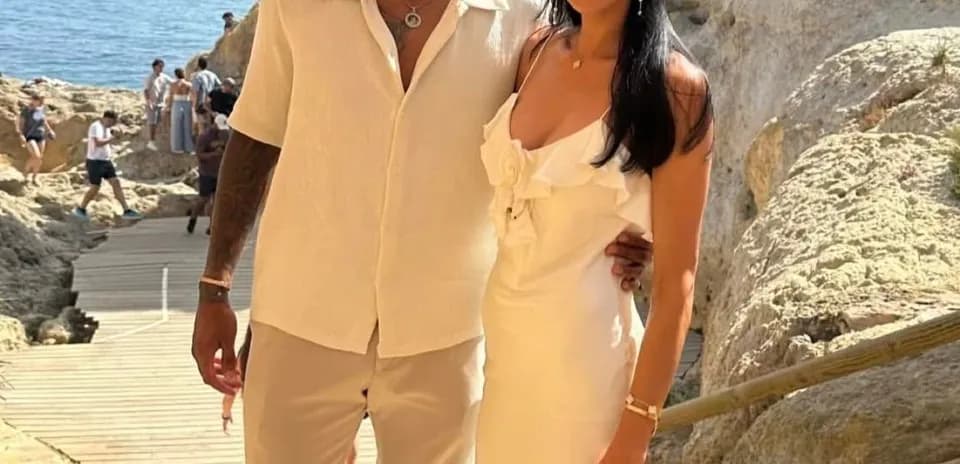 Pareja posando en la playa con fondo rocoso