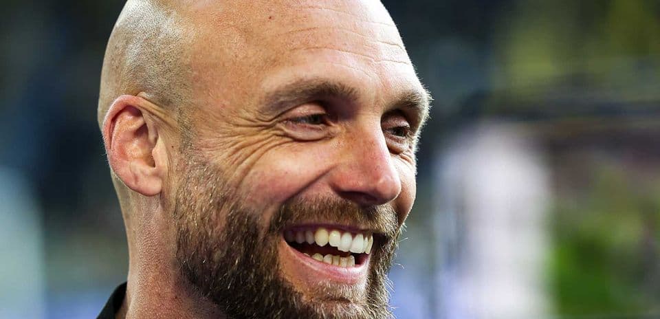 Hombre sonriendo con barba y cabeza rapada