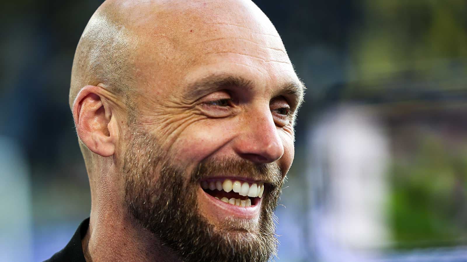 Hombre sonriendo con barba y cabeza rapada
