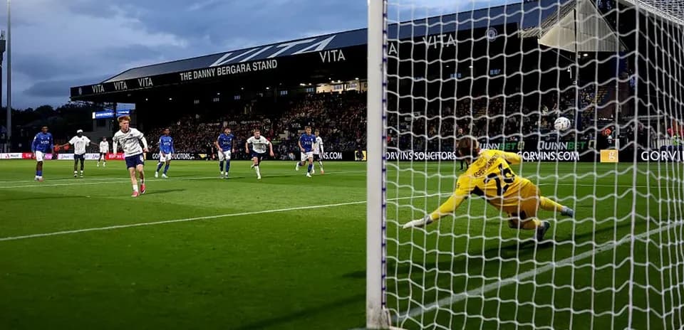 Jugador lanzando penalti mientras portero intenta detenerlo