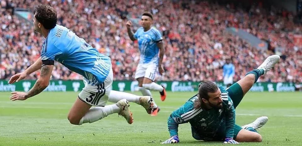 Jugador cae mientras el portero detiene el balón