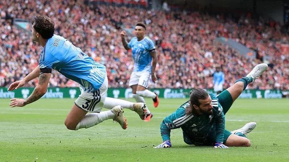 Jugador cae mientras el portero detiene el balón