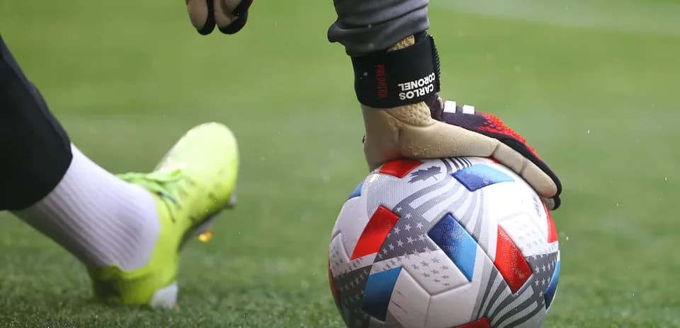 Portero sujetando balón en el campo de fútbol