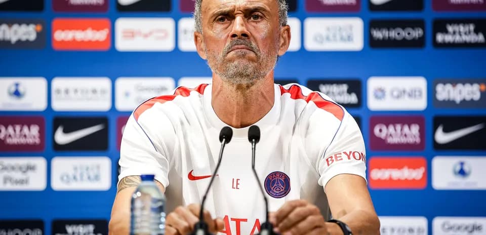 Entrenador en rueda de prensa con logotipo del PSG