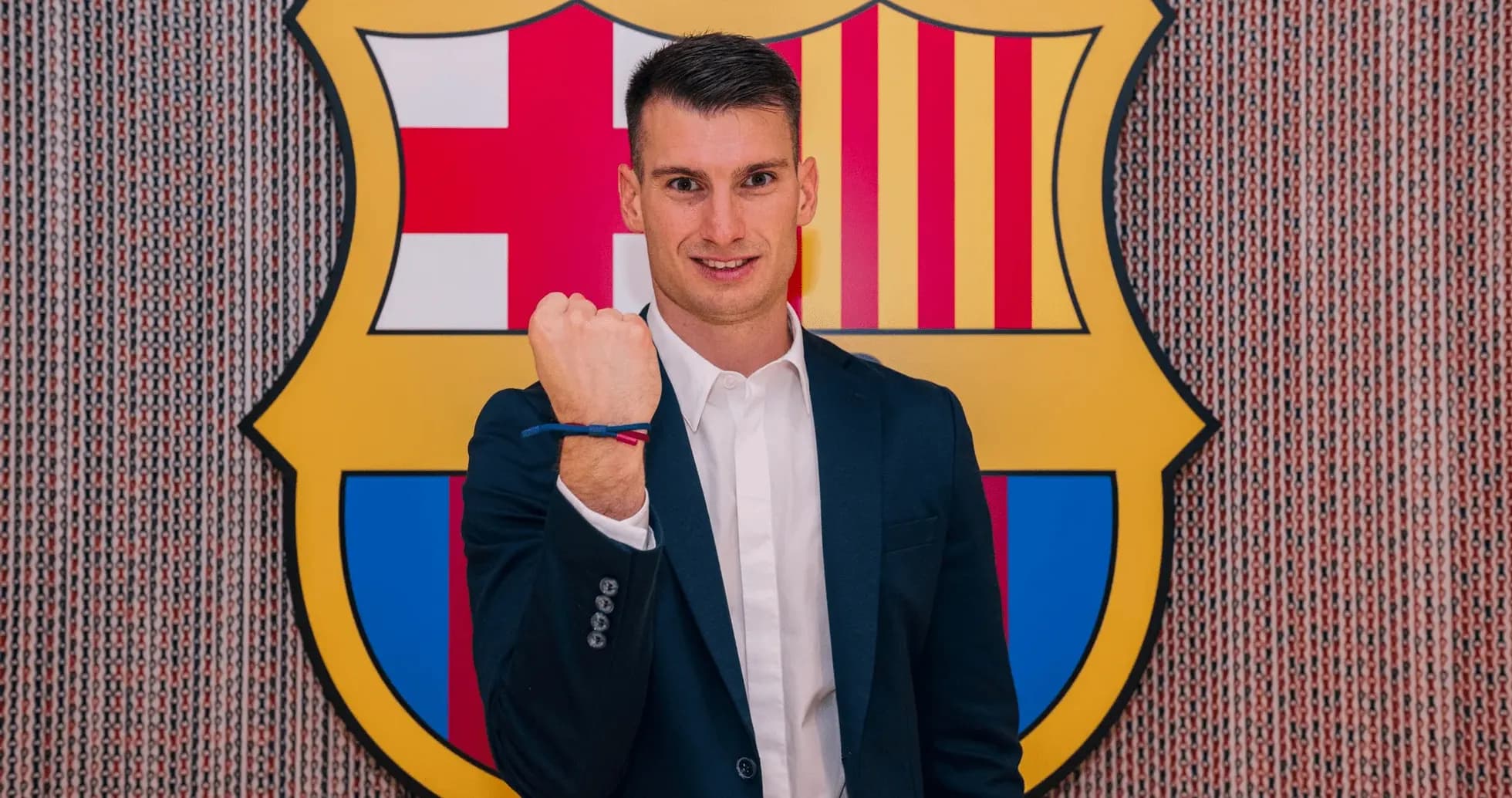 Jugador mostrando su puño frente al escudo del Barcelona