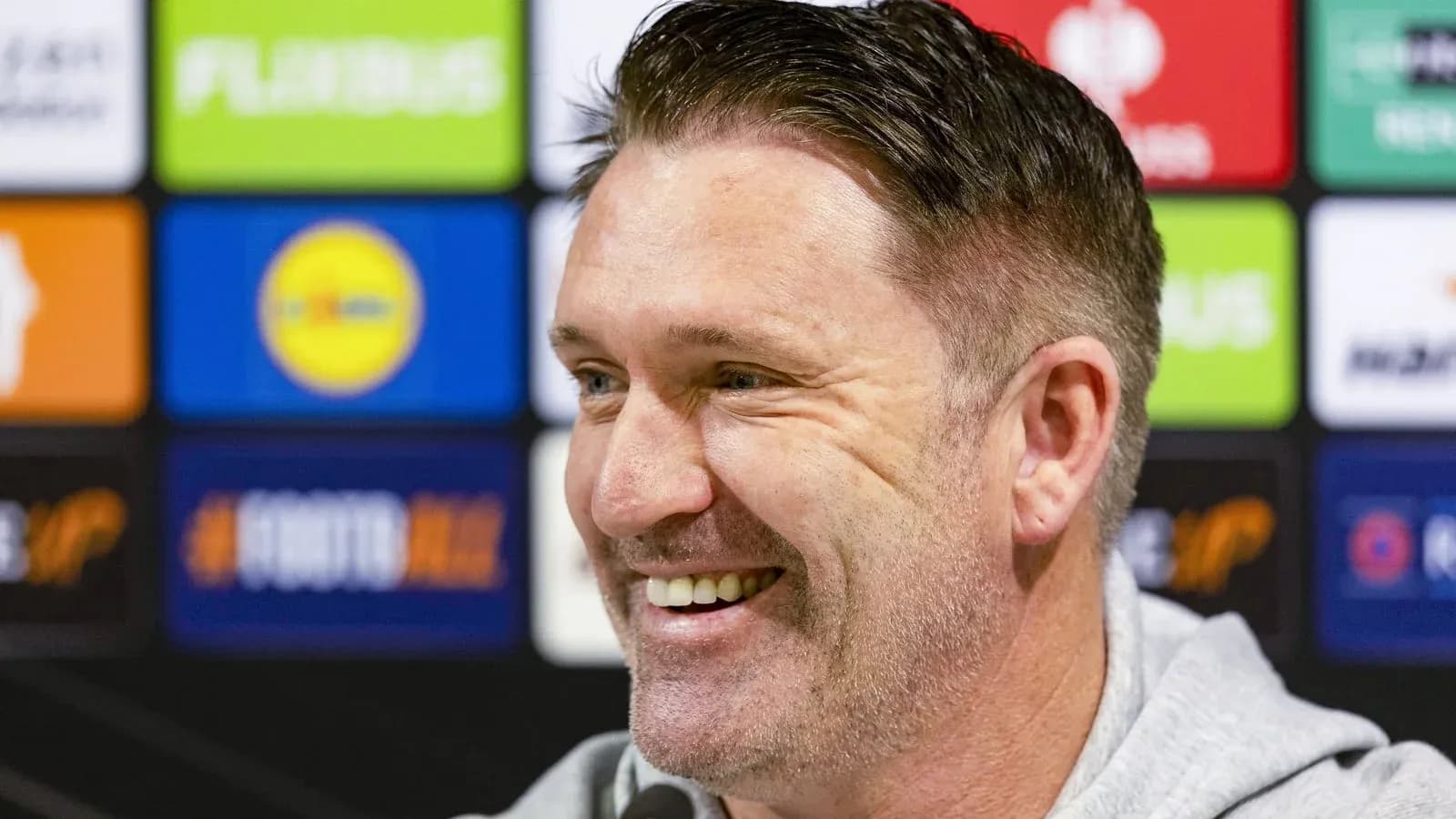 Entrenador sonriendo en conferencia de prensa