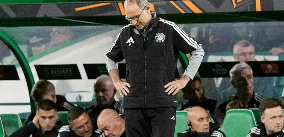 Entrenador de pie con cabeza agachada en banquillo