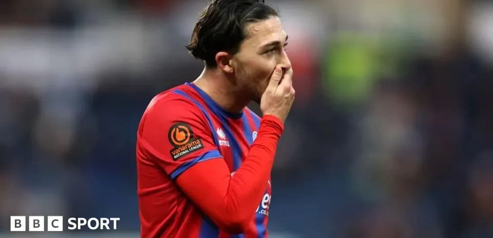 Jugador en uniforme rojo tocándose la cara durante el partido