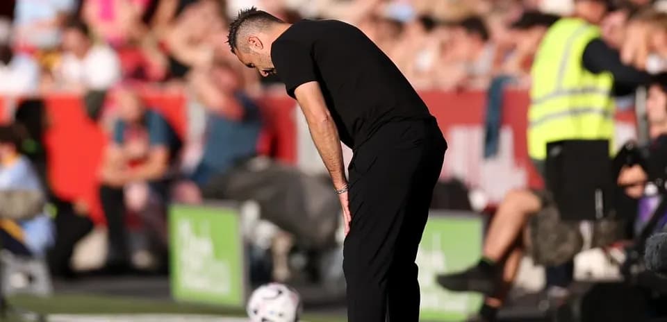 Entrenador agachado al lado del campo durante el partido