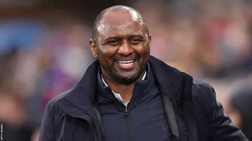 Entrenador sonriendo durante un partido de fútbol
