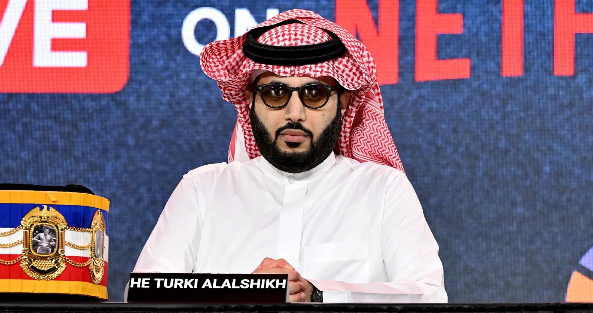 Hombre con gafas y keffiyeh en conferencia de prensa Hombre con gafas y keffiyeh en conferencia de prensa