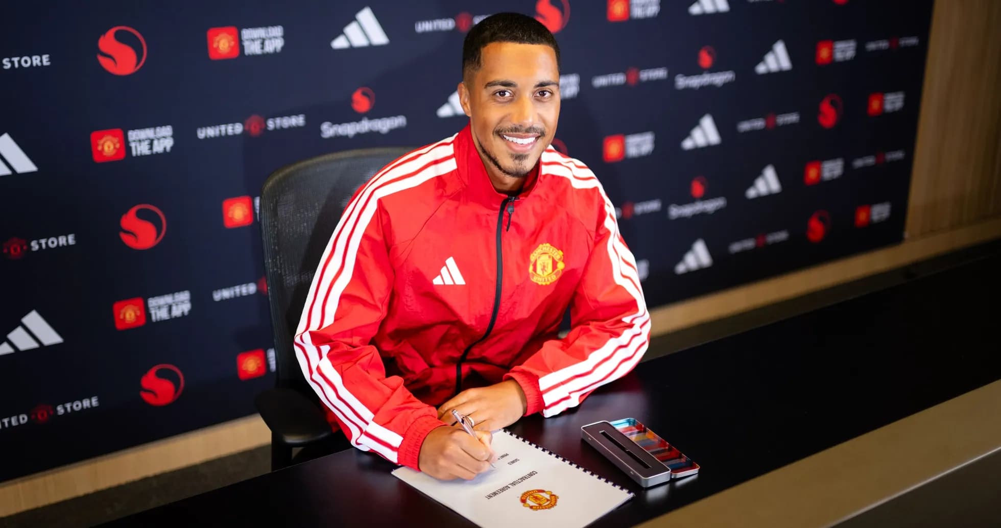 Jugador de Manchester United firmando contrato en mesa Jugador de Manchester United firmando contrato en mesa