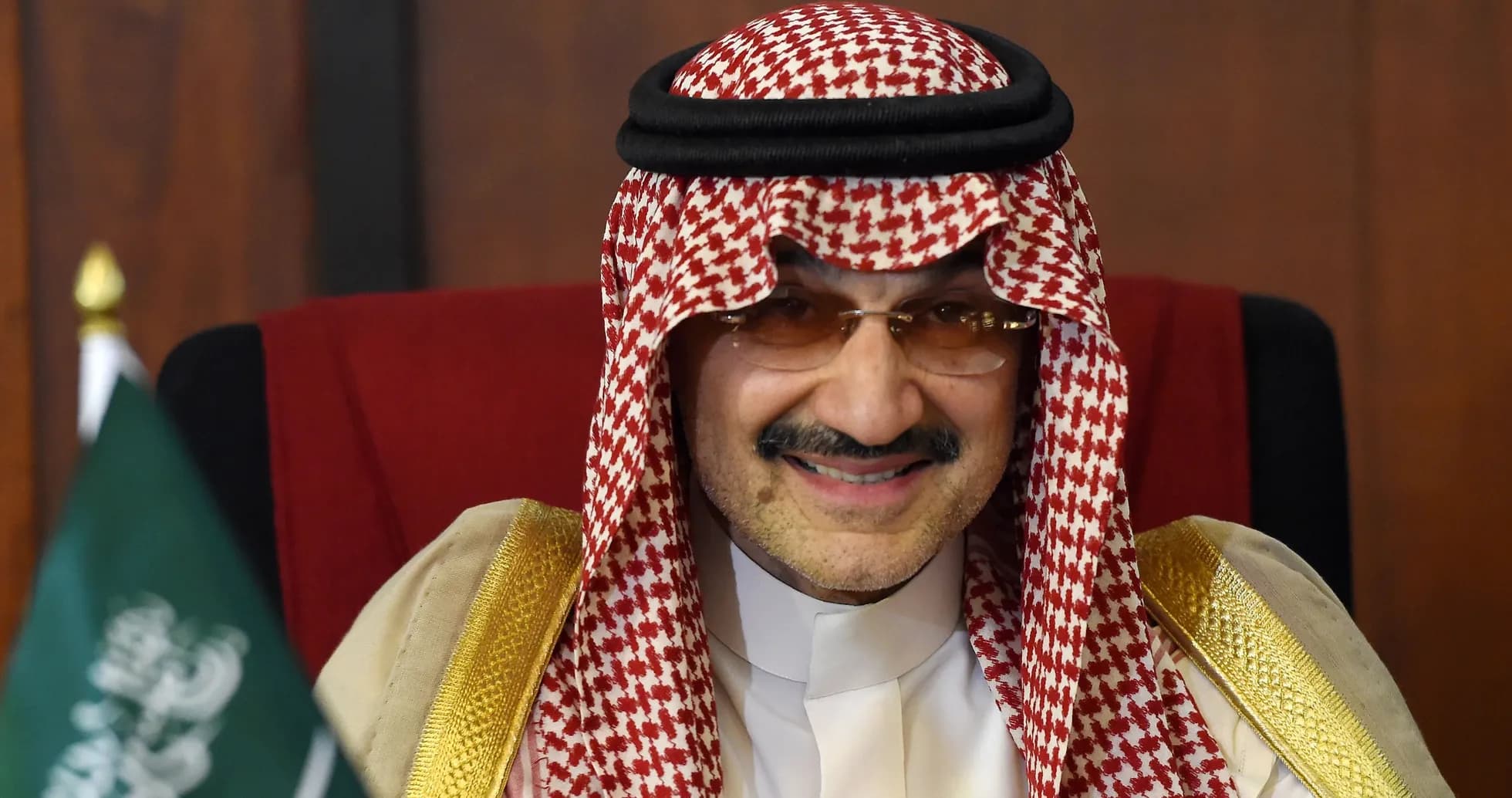 Hombre con thobe y ghutrah sonriendo en una silla Hombre con thobe y ghutrah sonriendo en una silla