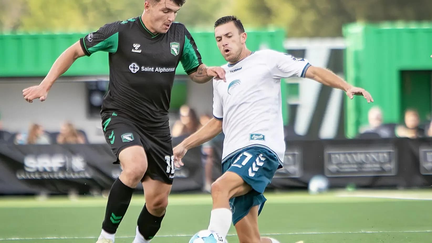 Dos jugadores compitiendo por el balón en el partido Dos jugadores compitiendo por el balón en el partido