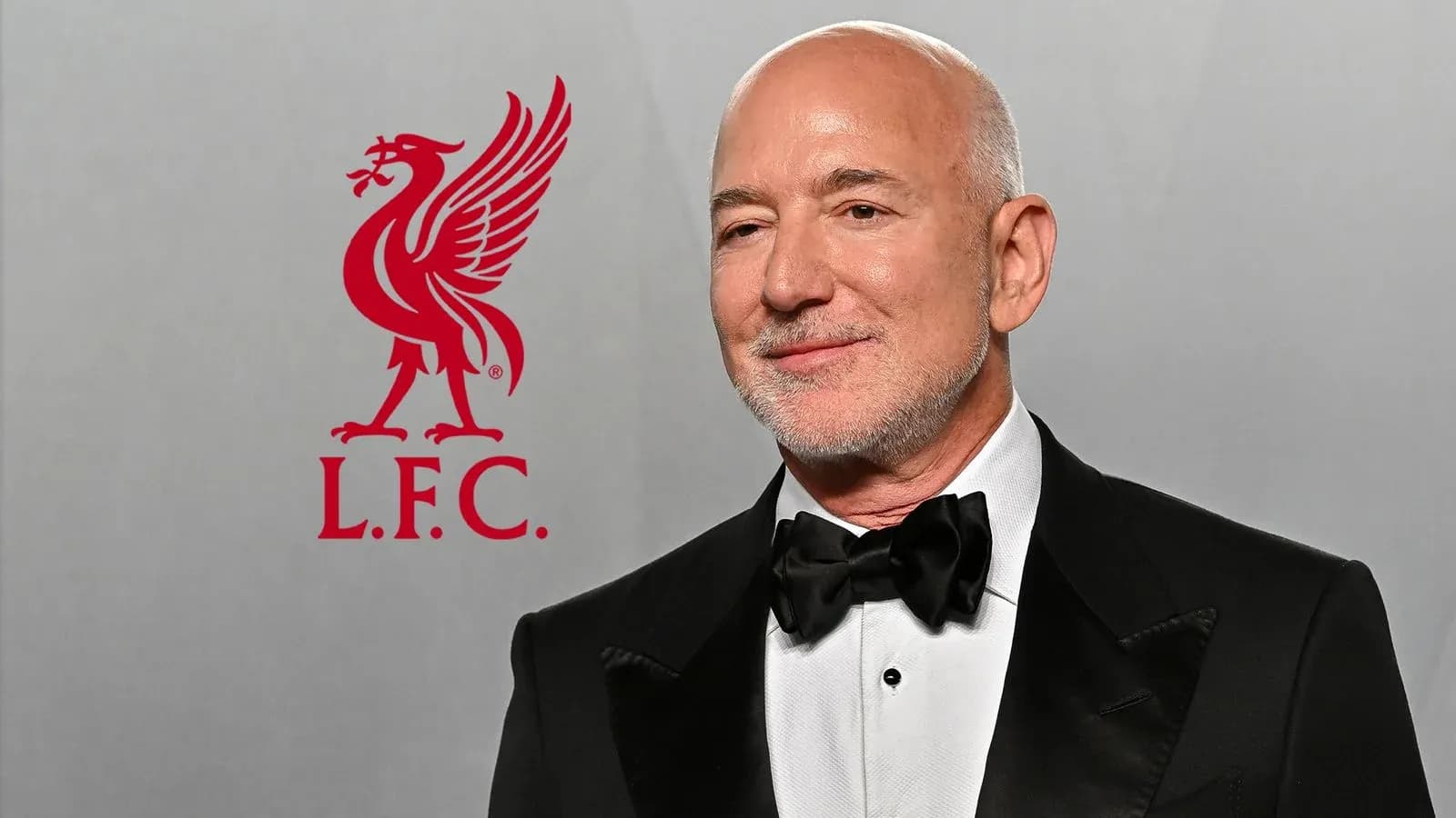 Hombre con traje formal junto al logo de Liverpool Hombre con traje formal junto al logo de Liverpool