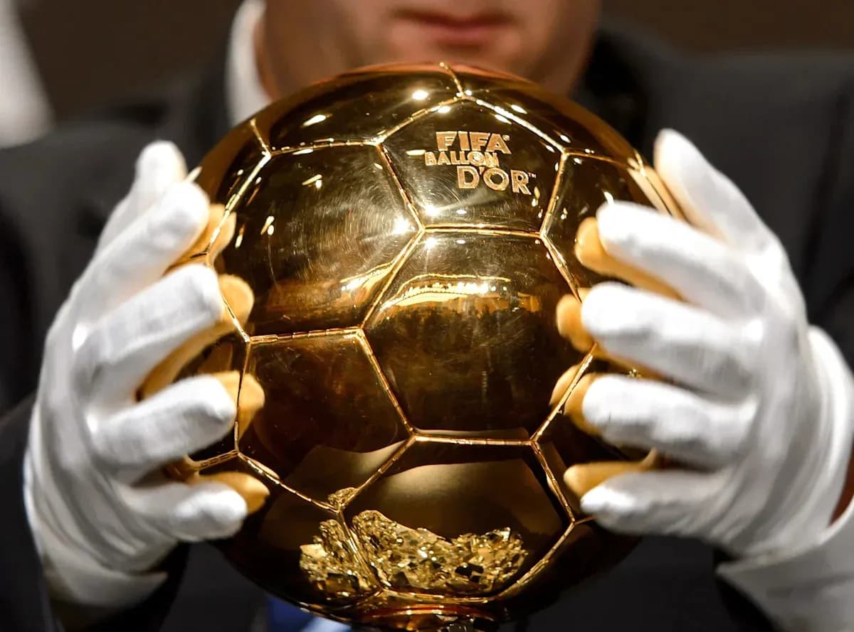 Trofeo Balón de Oro sostenido con guantes Trofeo Balón de Oro sostenido con guantes