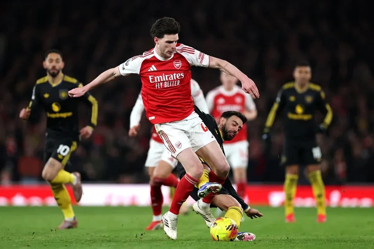Jugador de Arsenal esquivando a oponente caído Jugador de Arsenal esquivando a oponente caído