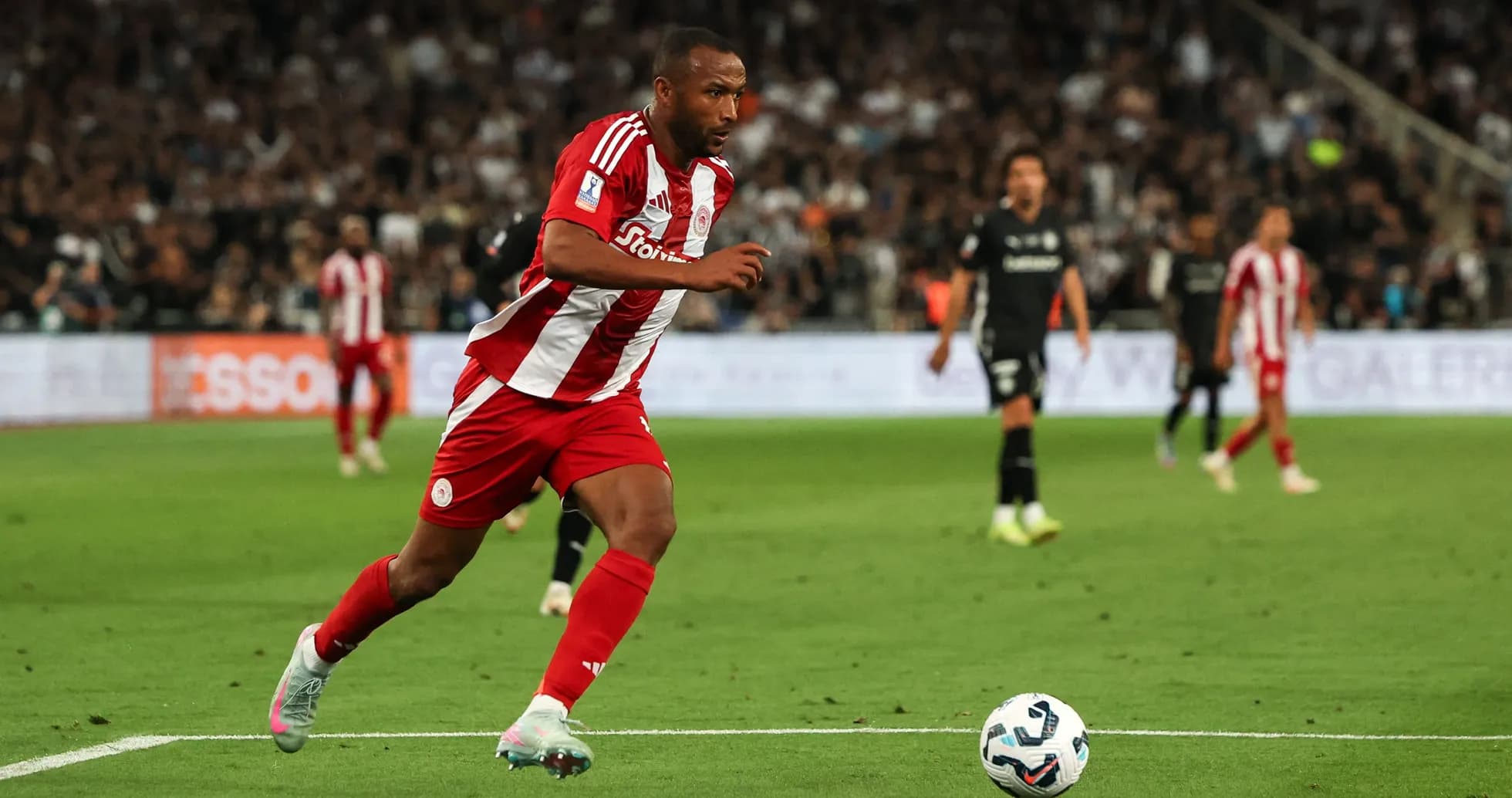 Jugador de Olympiacos corriendo hacia el balón en partido Jugador de Olympiacos corriendo hacia el balón en partido