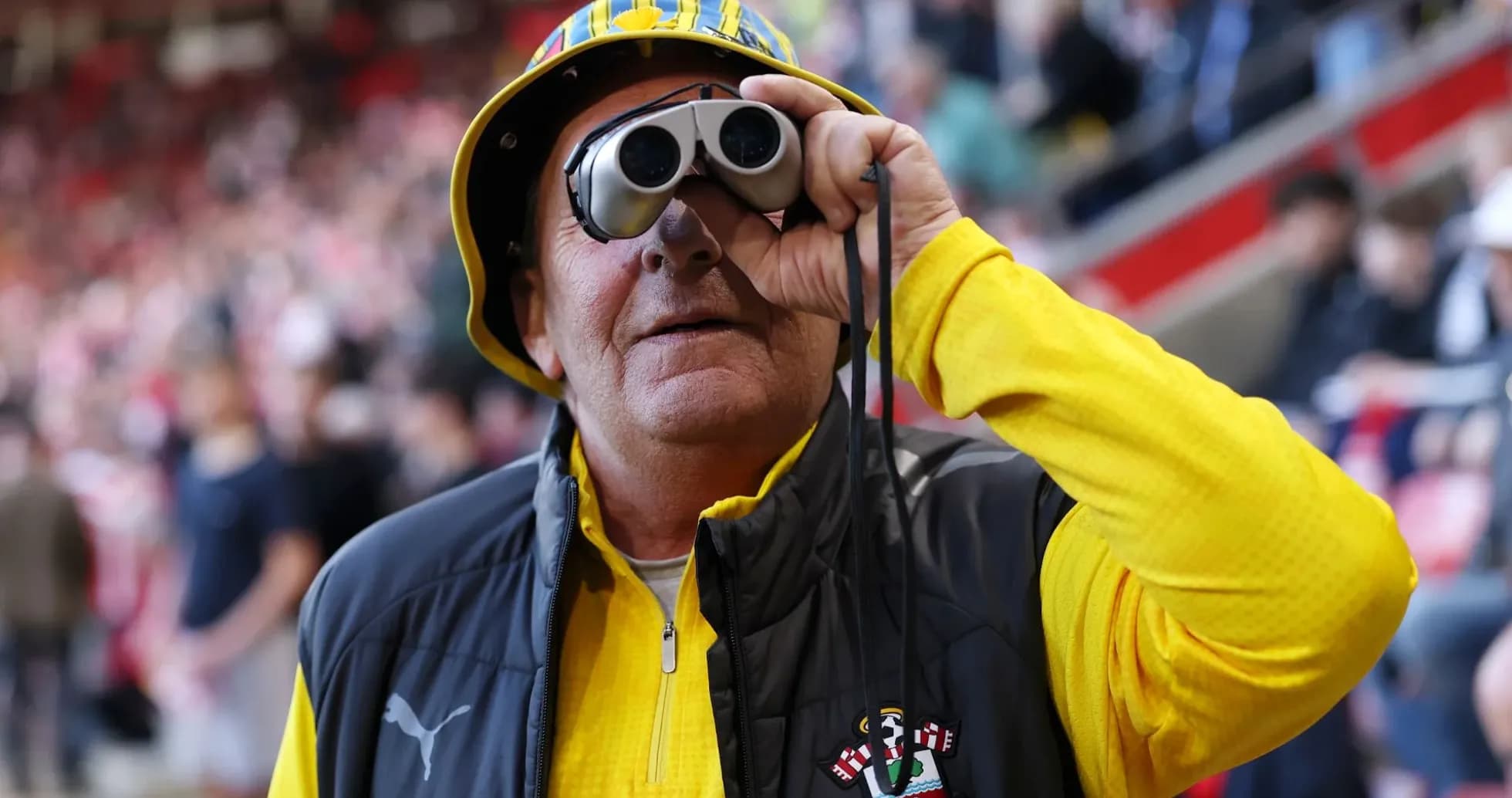 A fan wearing binoculars and a yellow hat A fan wearing binoculars and a yellow hat