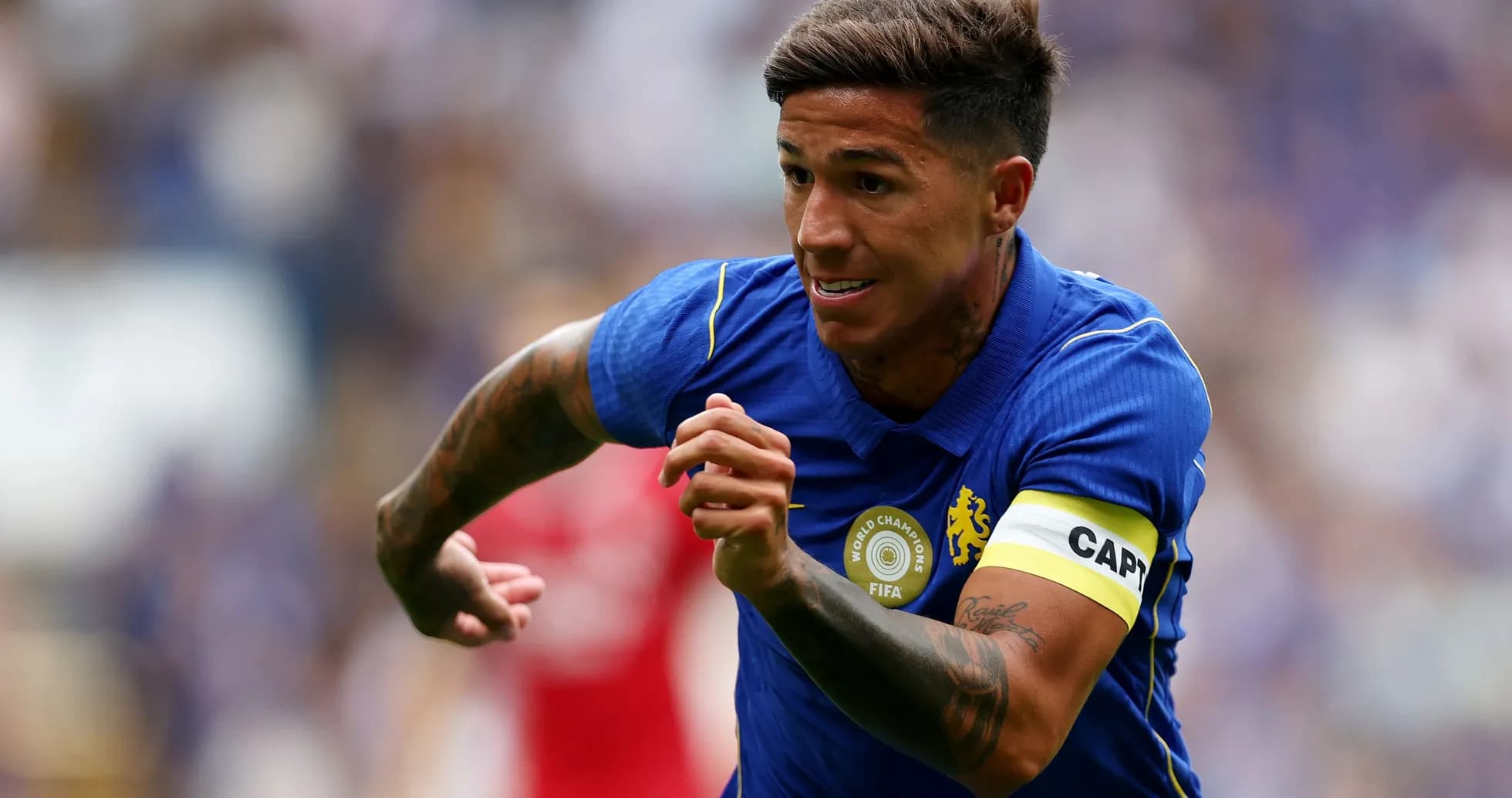 Jugador corriendo con camiseta azul y banda de capitán Jugador corriendo con camiseta azul y banda de capitán