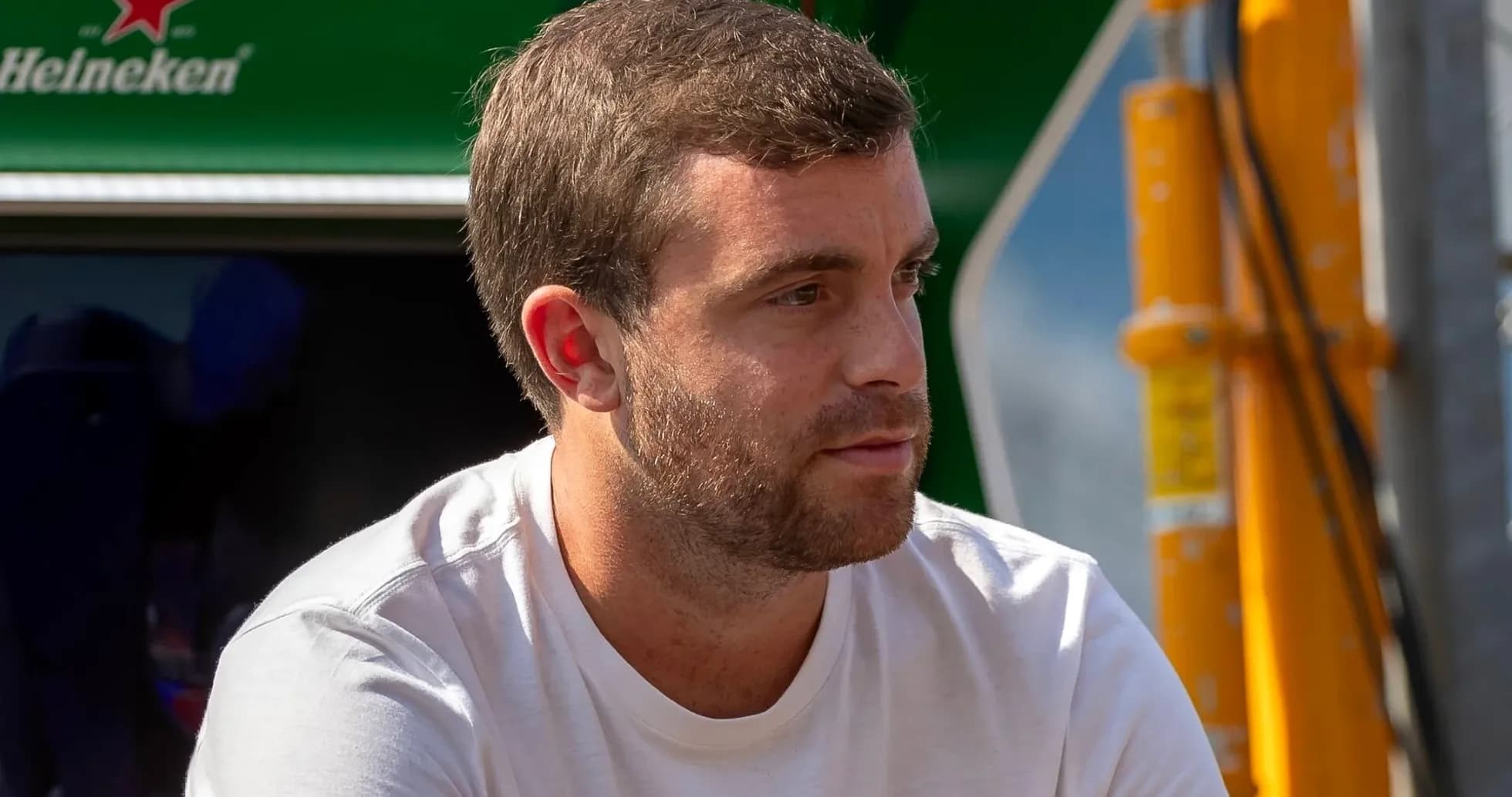 Hombre sentado con camiseta blanca, fondo verde Hombre sentado con camiseta blanca, fondo verde