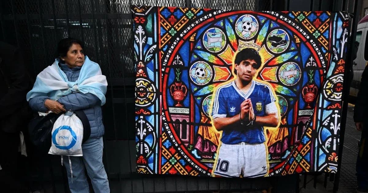 Mujer con bandera argentina frente a mural de Maradona Mujer con bandera argentina frente a mural de Maradona