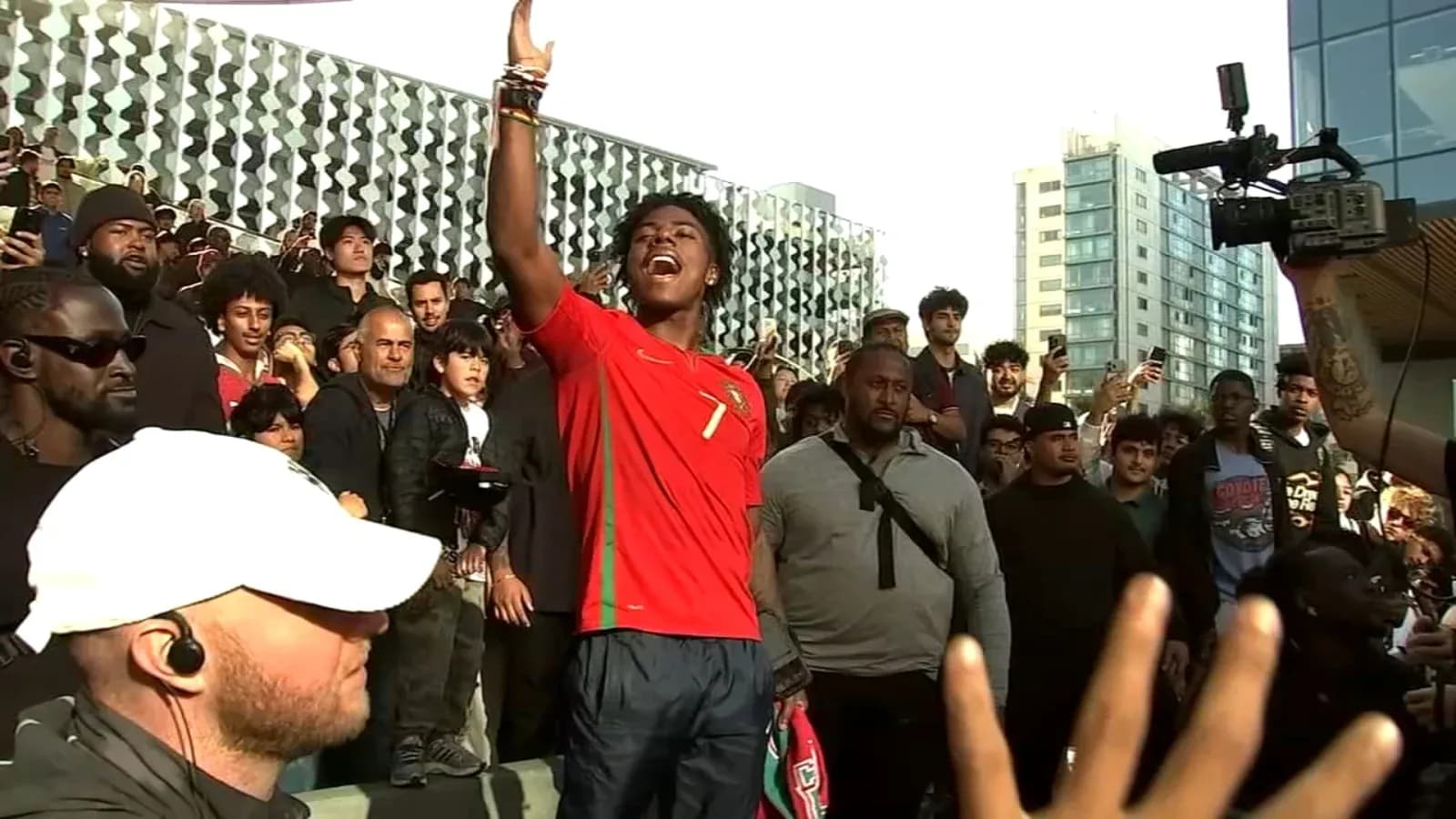 Joven con camiseta de Portugal levantando la mano en un evento Joven con camiseta de Portugal levantando la mano en un evento