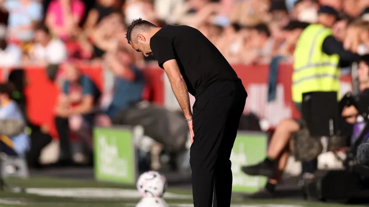 Entrenador agachado al lado del campo durante el partido Entrenador agachado al lado del campo durante el partido